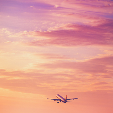 Airplane taking off at the sunset sky, silhouette of aircraft in the skyの写真素材