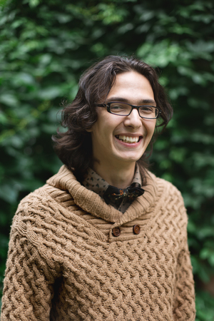 Young multiracial man smiling and standing against green background, looking at cameraの写真素材