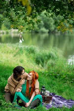 Young couple resting at the nature outdoors, picnic, couple embracing and kissingの写真素材
