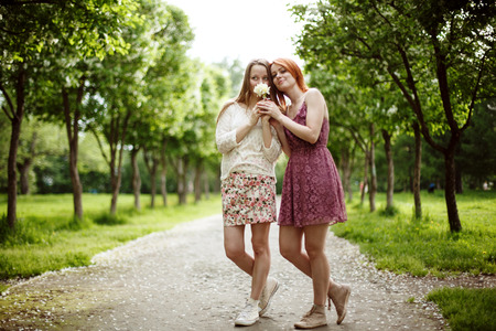 Friends concept, two young attractive women in summer dresses posing outdoorsの写真素材