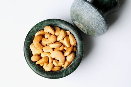 Roasted cashew nuts in a marble mortar on white background, top viewの写真素材