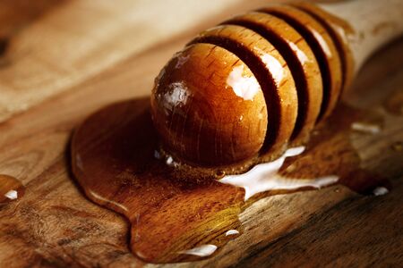 Honey spoon, special wooden dipper for liquid honey product close-up on a wooden background, selective focusの写真素材