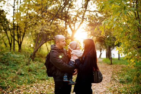 Happy family, mother, father and little son having fun in the park at the sunset. Real people.の写真素材