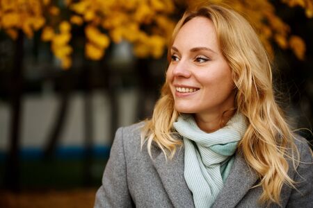 Headshot of pretty smiling blonde woman at the autumn nature with copy spaceの写真素材