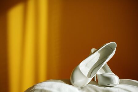White wedding shoes on yellow background with beautiful natural light, copy spaceの写真素材