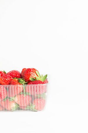 Natural red strawberries in a plastic transparent container on white backgroundの写真素材