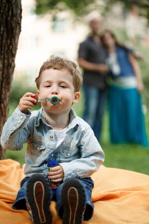 Cute funny toddler boy playing with soap bubbles outdoorsの写真素材