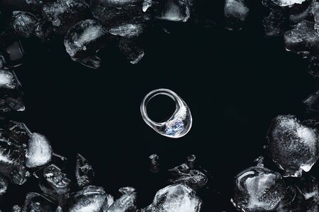 Transparent icy rings made from glass in ice and water, top view on black backgroundの写真素材