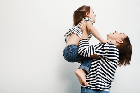 Happy mother holding adorable kid on her hands and laughing, white backgroundの写真素材