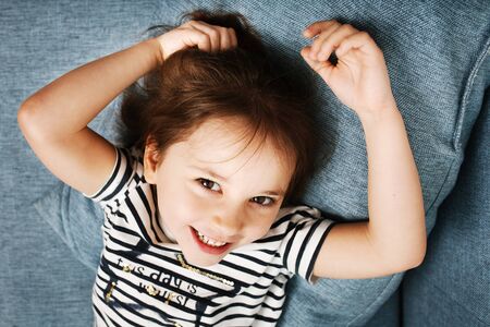 Adorable little girl in striped clothes smiling and laughing looking at camera, close-up portrait
