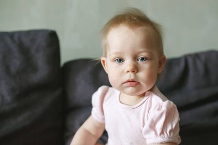 Sweet serious little infant girl portrait close-up, looking at camera, want to sleep