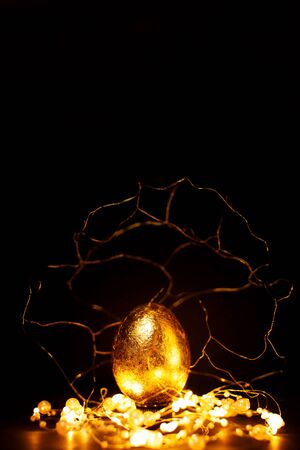 Luxury easter golden egg in gold decorations with lights over dark background, magic of easter...
