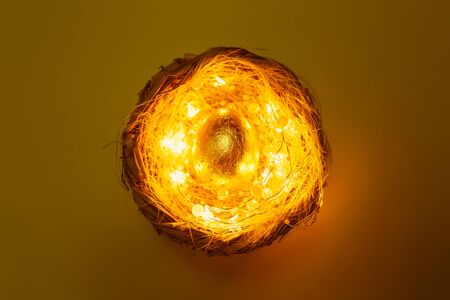 Golden egg in the nest with lights over pastel background, mystery easter concept, top viewの写真素材