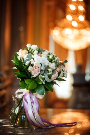Luxurious bouquet of pink and white creamy roses with beautiful ribbons in interior, wedding day flowersの写真素材