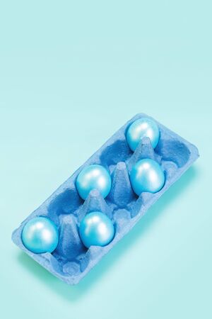 Five pearl blue colored eggs in cardboard market blue tray, modern trendy easter conceptの写真素材