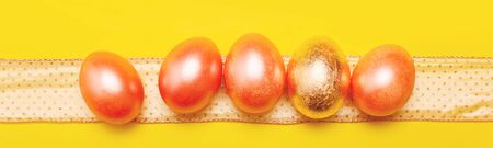 Modern trendy easter concept with five colored pink and golden eggs over bright yellow background, bannerの写真素材