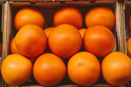 Fresh ripe grapefruits in a carton box on a fruit market, organic natural food backgroundの写真素材