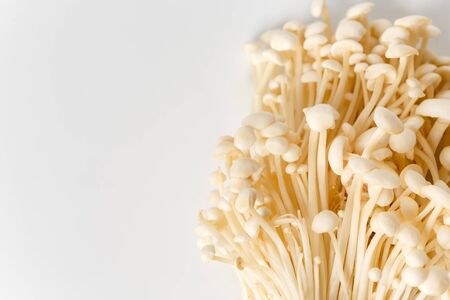 Enoki, Enokitake, Flammulina velutipes, edible mushroom popular in Japanese cuisine. Heap of little white enoki mushrooms on neutral white background, close-up.の写真素材