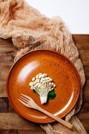 Enoki, Enokitake, Flammulina velutipes, edible mushroom popular in Japanese cuisine. Heap of little white mushrooms served on ceramics plate, dieting, close-up.の写真素材