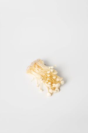 Enoki, Enokitake, Flammulina velutipes, edible mushroom popular in Japanese cuisine. Heap of little white enoki mushrooms on neutral white background, close-up.の写真素材