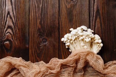 Enoki, Enokitake, Flammulina velutipes, edible mushroom popular in Japanese cuisine. Heap of little white mushrooms served on wooden brown background close-up.の写真素材