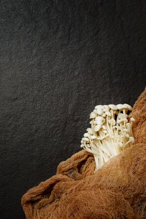 Enoki,  Enokitake, Flammulina velutipes, edible mushroom popular in Japanese cuisine. Heap of little white mushrooms served on neutral black background with copy space.の写真素材