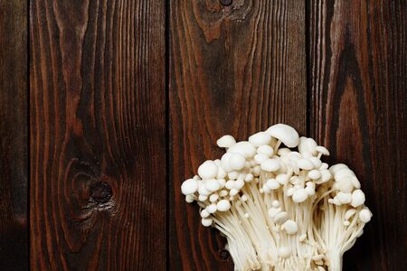 Enoki, Enokitake, Flammulina velutipes, edible mushroom popular in Japanese cuisine. Heap of little white mushrooms served on wooden brown background close-up with copy space.の写真素材