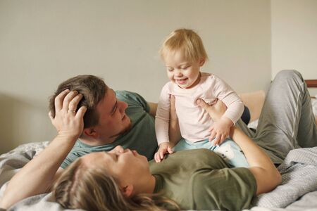 Happy family with little girl child in the morning lying in bedroom and smilingの写真素材