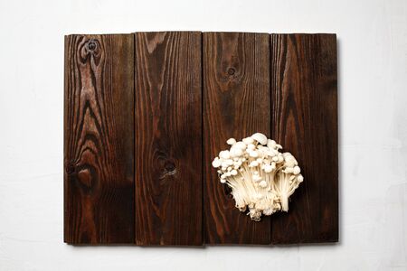 Enoki,  Enokitake, Flammulina velutipes, edible mushroom popular in Japanese cuisine. Heap of little white mushrooms served on wooden brown background with copy space.の写真素材