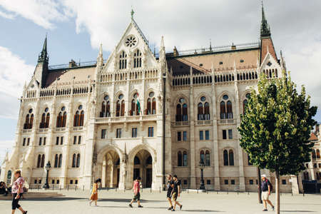 BUDAPEST, HUNGARY - July 23, 2019 - View on famous touristic place Hungarian parliament with tourists walking in front of it in summer dayのeditorial素材