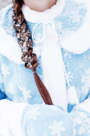 Close-up of woman braided hair in snow, girl in traditional russian suit of snow maiden, new year and christmas holiday girlの写真素材