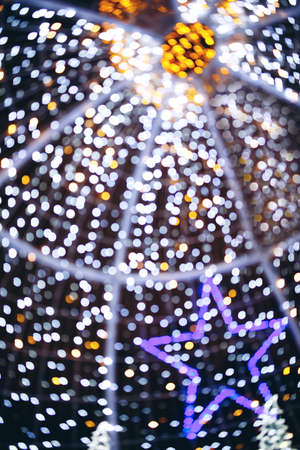 Abstract night holiday background with defocused Christmas illumination and star shape