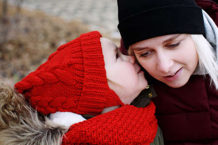 Cute little preschool daughter whispering a secret to young beautiful smiling mother, concept of bondingの写真素材