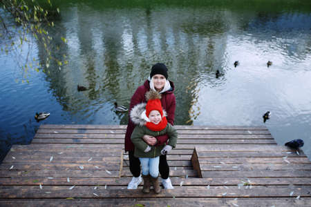 Young mother walking with her cute little daughter outside in urban park near riverの写真素材