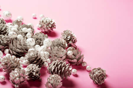 Christmas festive arrangement with silver pine cones and small glitzy balls on bright pink background, copy spaceの写真素材