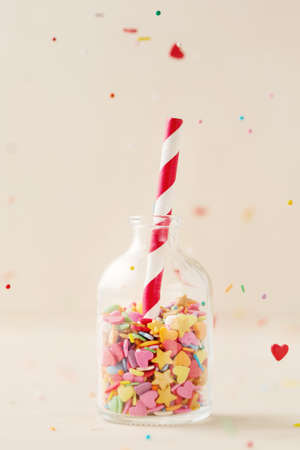 Colorful heart and star sprinkling in a little bottle with striped red and white straw, selective focusの写真素材