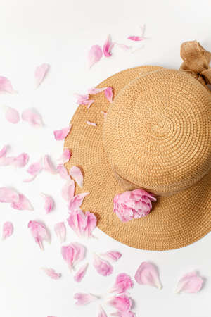 Summer, spring concept, straw braided hat, pink peony flowers and petals on white background, top viewの写真素材