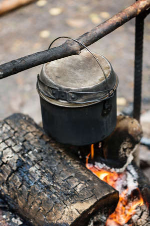 Camp fire, cooking dinner outdoors at the nature, pot over bonfire, close-upの写真素材