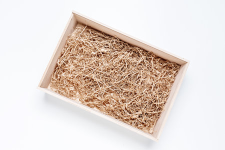 Opened gift wooden box with shredded paper filler on white background for product placement. Top view, mockupの写真素材