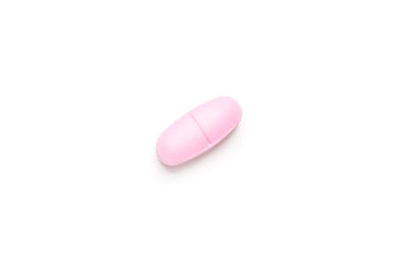 One single pink pill on white background, multivitamin tablet or dietary supplement close-upの写真素材