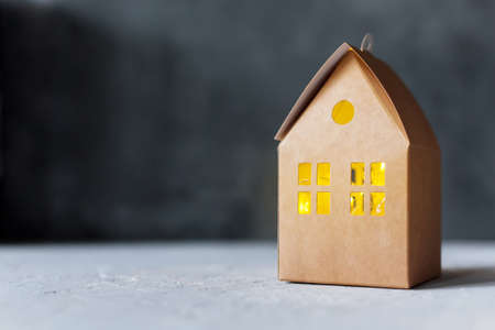 Craft cardboard box house with luminous window, creative gift packaging on gray backgroundの写真素材