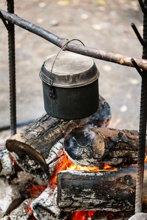Camp fire, cooking dinner outdoors at the nature, pot over bonfire, close-upの写真素材