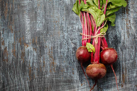 Bundle of fresh organic farmer young beetroots on dark scratched background, close-up, top view....