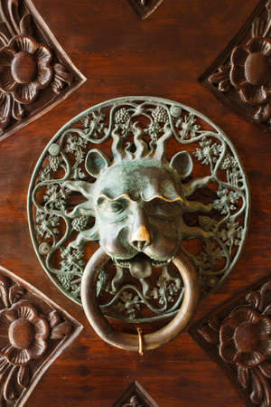Vintage ancient door knob as lion head made from bronze on wooden surfaceの写真素材
