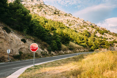 Red stop sign near the mountain road in countrysideの写真素材