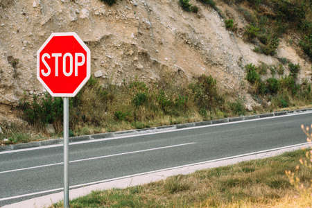 Red stop sign near the mountain road in countrysideの写真素材
