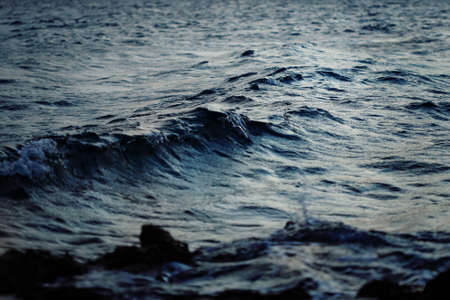 Dark deep blue sea water with waves in twilight, serene and calming natural water backgroundの写真素材