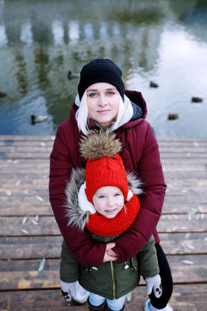 Young mother walking with her cute little daughter outside in urban park near riverの写真素材