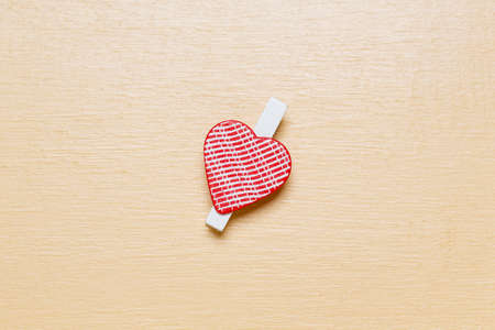 Minimalistic simple Valentine`s day card, little red heart on beige wooden surface