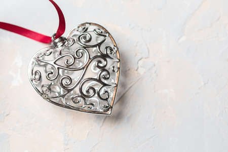 Saint Valentine day greeting card, beautiful silver heart with red ribbon on gray textured...